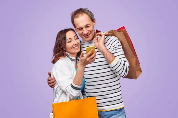 Casal adulto usando smartphone durante as compras — Fotografia de Stock