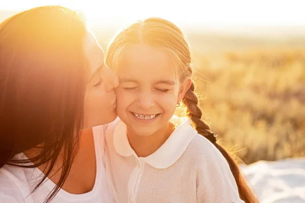 Mãe beijando criança durante o pôr do sol — Fotografia de Stock