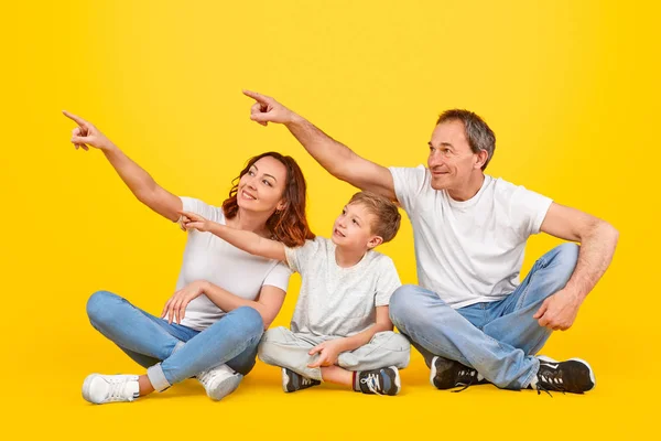 Szczęśliwa rodzina wskazuje na bok razem — Zdjęcie stockowe