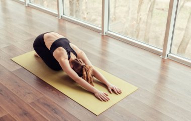 Yoga yaparken omurilik kaslarını geren kadın çocuk pozu veriyor