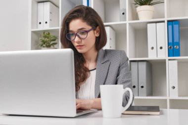 Ofiste dizüstü bilgisayar kullanan genç kadın