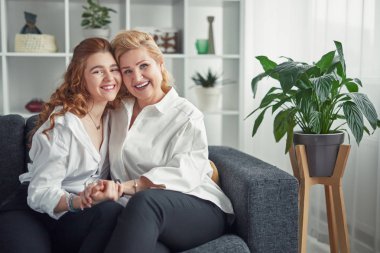 Gülümseyen anne ve kızı kanepede