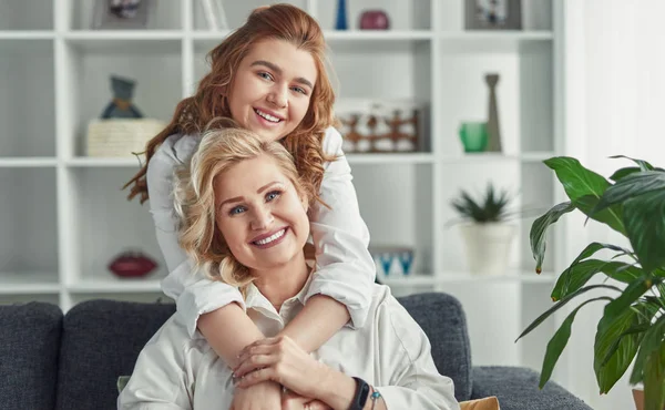 Glückliche Oma und Enkelin Freunde umarmen sich auf der Couch zu Hause — Stockfoto