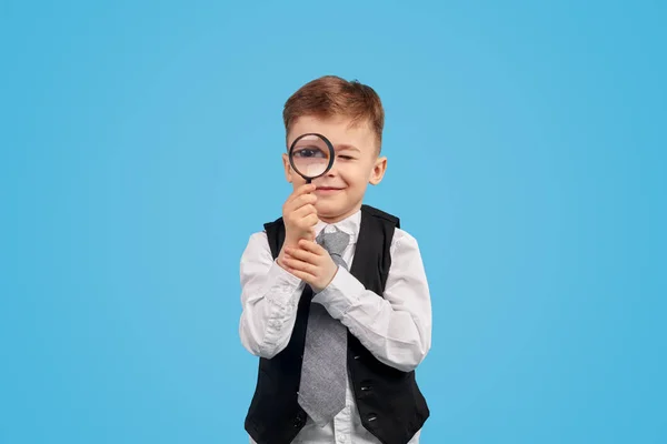 Schattige school jongen die door vergrootglas kijkt — Stockfoto