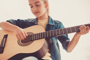 Genç kız özenle gitar çalıyor