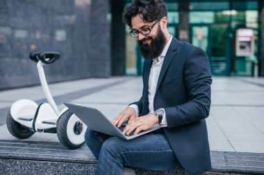 Gülümseyen adam dizüstü tarama ve hover board yakınında rahatlatıcı