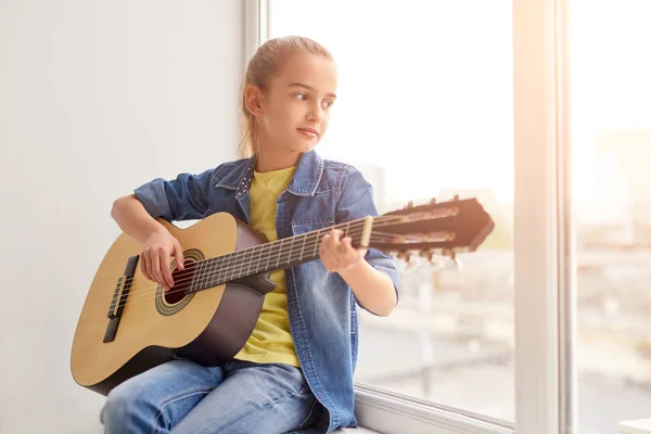 Ragazza che suona la chitarra vicino alla finestra — Foto Stock
