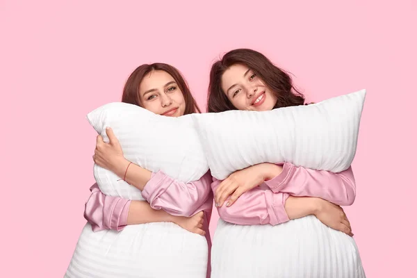 Jovens mulheres abraçando almofadas macias durante a festa do pijama — Fotografia de Stock