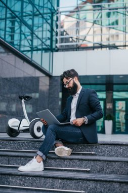 Freelancer sokakta gyroscooter yakın dizüstü bilgisayar kullanarak