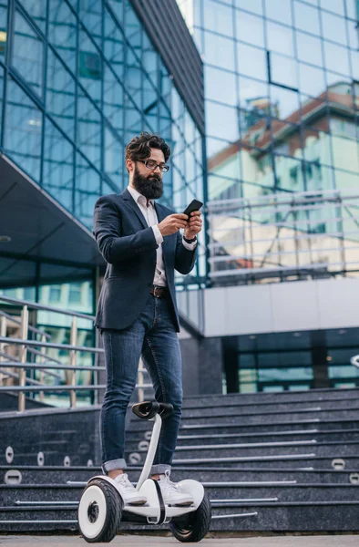 Bärtiger Manager mit Smartphone auf Hoverboard — Stockfoto