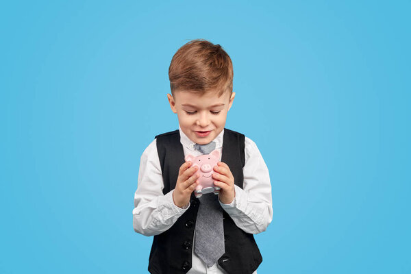 Любопытный мальчик смотрит на копилку
