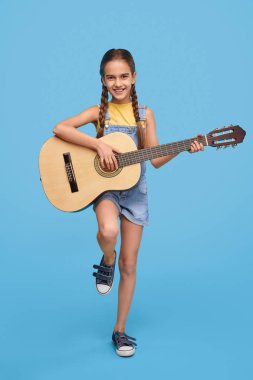Gülümseyen kız gitar çalmak ve kameraya bakıyor