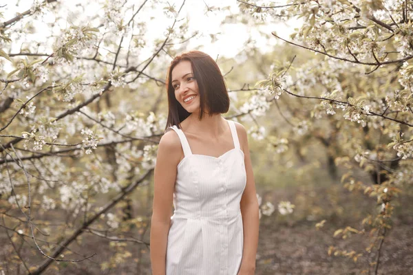 Uśmiechnięta kobieta pośród kwitnących drzew w ogrodzie — Zdjęcie stockowe