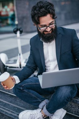 Dizüstü bilgisayar kullanarak içecek ile Gülümseyen yönetici