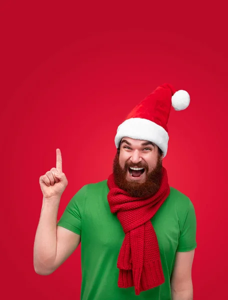 Homem excitado de chapéu de Natal apontando para cima — Fotografia de Stock