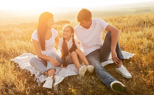 Happy family resting on blanket in field — Stock Photo, Image