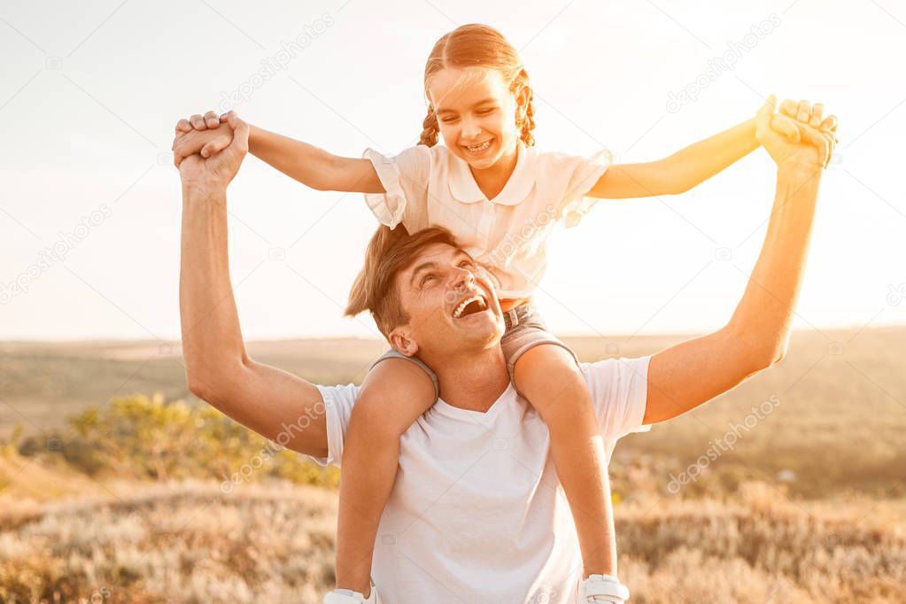 Excited father carrying daughter on neck