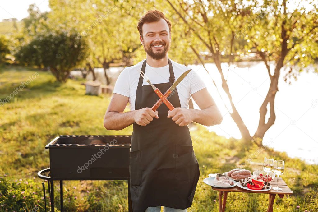 Smiling chef crossing utensils during picnic