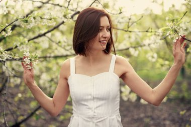 Gülümseyen bayan çiçek açan dallara dokunuyor