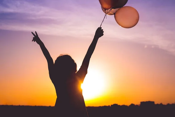 Anonyme Frau mit Luftballons bei Sonnenuntergang — Stockfoto