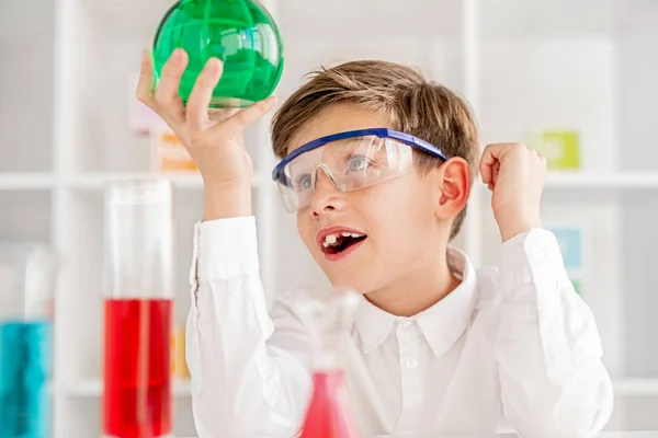 Zdziwiony chłopiec badając płyn chemiczny w kolbie — Zdjęcie stockowe