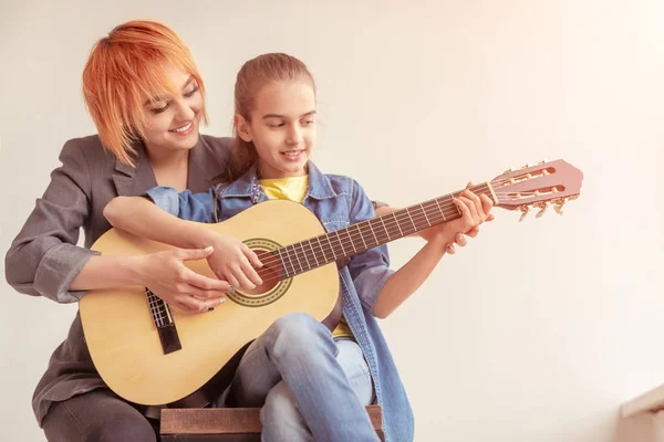 ギターを弾くために女の子を教える女性 — ストック写真
