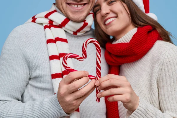 Casal de colheita fazendo coração de bengalas doces durante o Natal — Fotografia de Stock