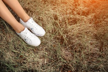 Doğada çimenlerin üzerinde oturan spor ayakkabılı kırpma kadın