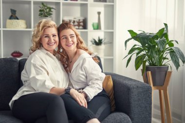 Neşeli anne ve kızı kanepede