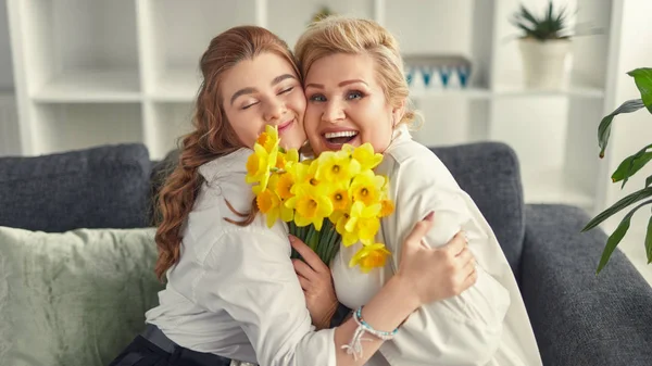 Lachende grootmoeder en kleindochter knuffelen en houden bloemen — Stockfoto