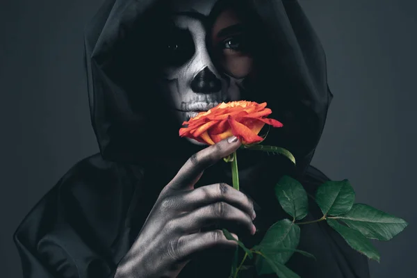 Hátborzongató nő fekete köpenyben vörös rózsával — Stock Fotó