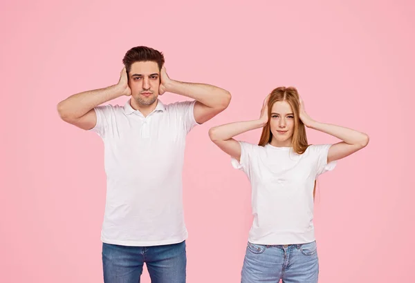 Young couple covering ears during quarrel