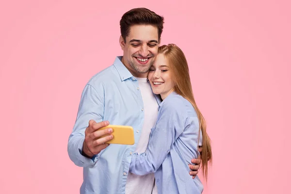 Glückliches Paar umarmt und nutzt Smartphone — Stockfoto