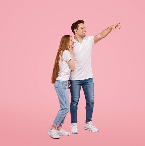 Couple in white t-shirts looking away pointing with finger