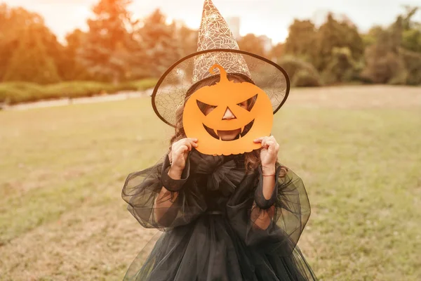 Kleines Mädchen mit Halloween-Kürbismaske steht im Feld — Stockfoto