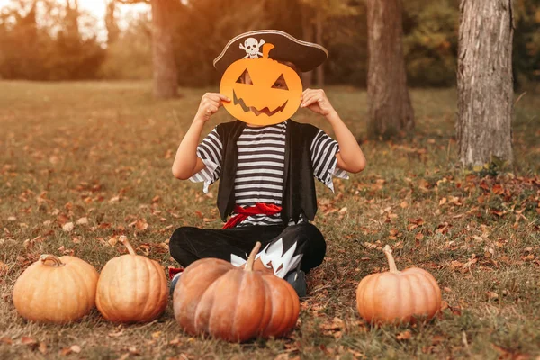 Funny kid with pumpkins and paper mask — Stock Photo, Image