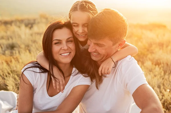 Glada dotter kramar föräldrar på ängen — Stockfoto