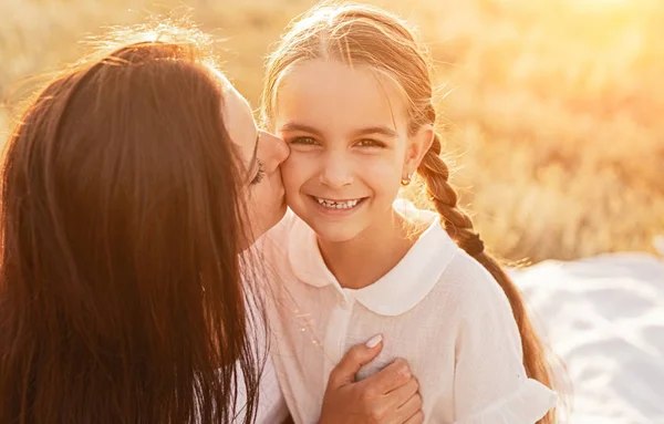 Mor kramar och kysser dotter med kärlek på picknick i fält — Stockfoto