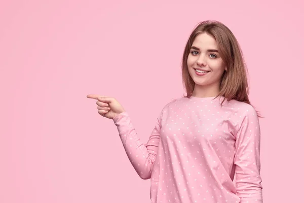 Mulher atraente apontando para longe e sorrindo — Fotografia de Stock