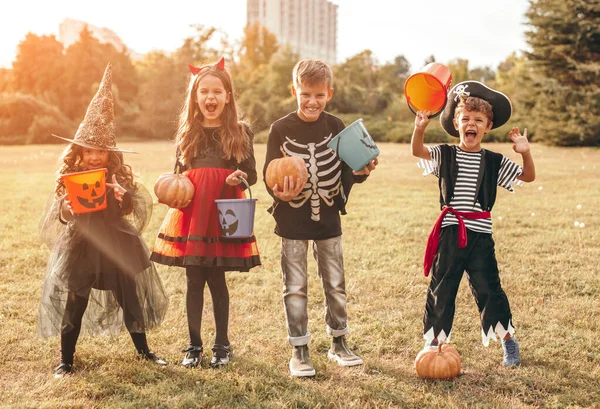 Fröhliche kleine Kinder in Halloween-Kostümen stehen auf dem Feld — Stockfoto
