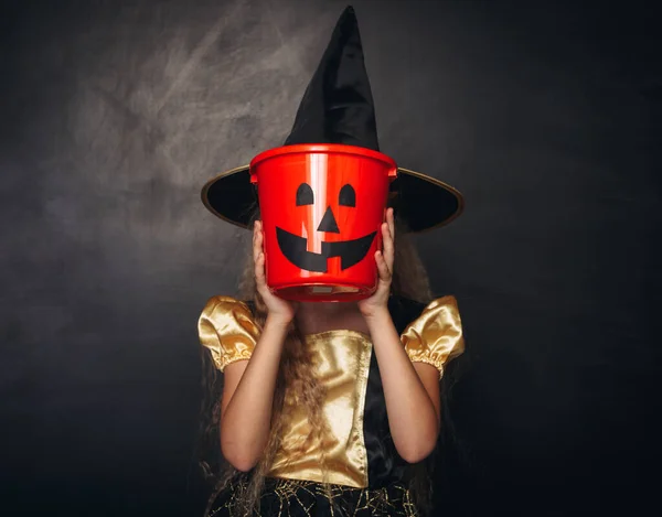 Pequeno rosto de cobertura de bruxa com balde de abóbora doce — Fotografia de Stock
