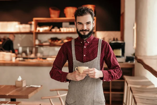 Barbudo barista con taza de café en la cafetería — Foto de Stock