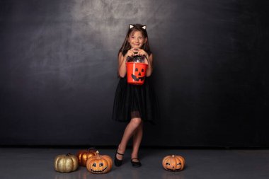 Kırmızı şeker kovalı kedi kostümlü pozitif kız.