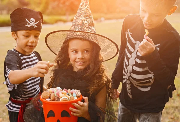 Happy kids in Halloween costumes with candy collector — Stock Photo, Image