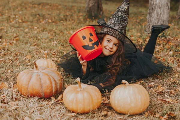 Cute girl with pumpkins and empty candy collector — Stock Photo, Image