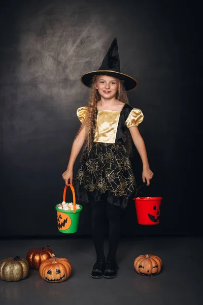 Kleine heks met kleurrijke pompoenemmers — Stockfoto