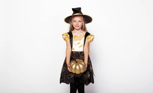 Pequena bruxa segurando abóbora dourada decorativa — Fotografia de Stock