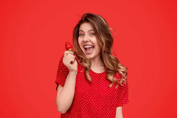 Excited woman in bright dress carrying strawberry — Stockfoto