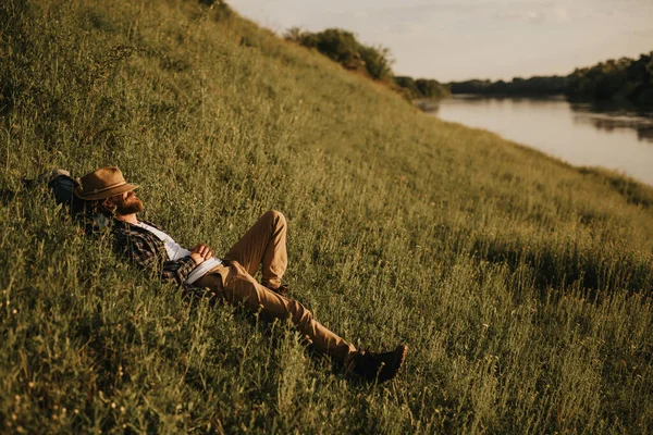 Penjelajah laki-laki beristirahat di bukit dekat sungai — Stok Foto