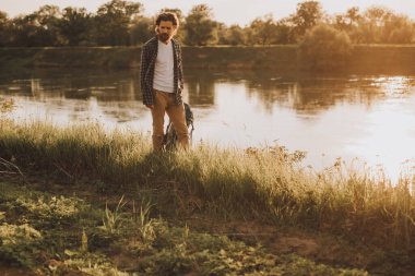Akşam vakti göl kıyısında yürüyen bir yürüyüşçü.